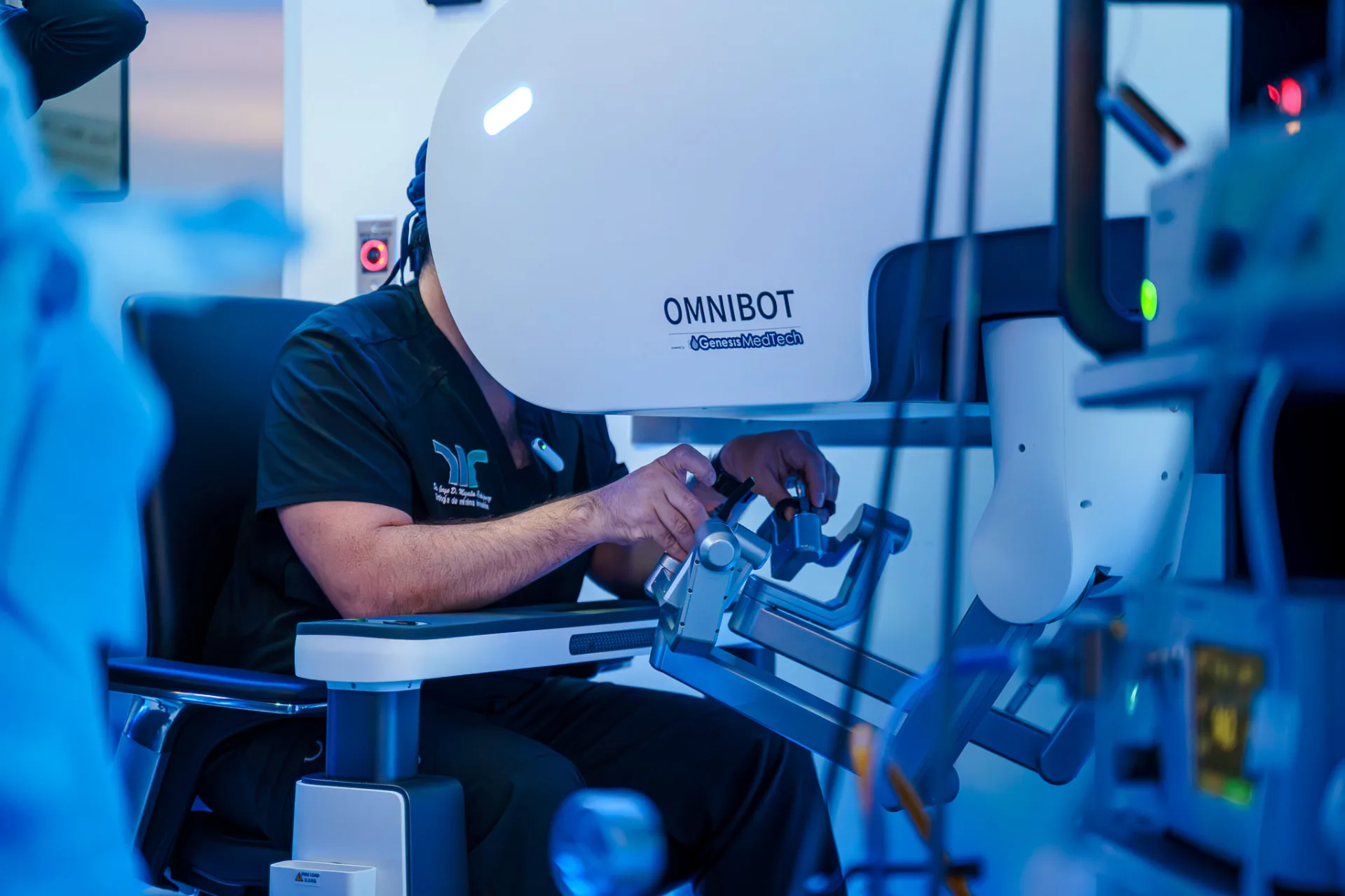 Surgeon seated at the OMNIBOT MP 1000 surgeon console, hands on the master controllers while viewing the stereoscopic display